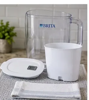 A clean pitcher, reservoir, and lid air-drying separately on a fresh kitchen towel.
