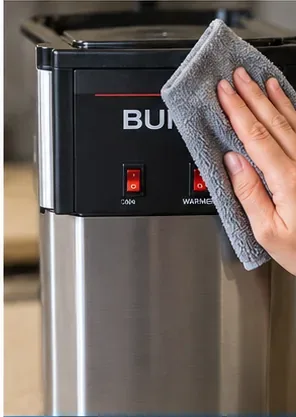 Soft microfiber cloth wiping the stainless and black exterior of a BUNN-style coffee maker