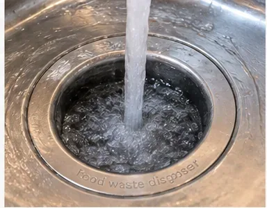 Cold water flushing through a running garbage disposal after the ice has been ground