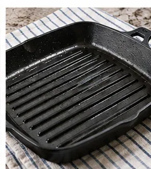 A freshly cleaned ridged grill pan drying on a striped kitchen towel after washing.