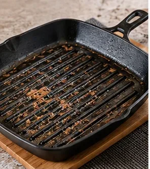 A black ridged grill pan with browned food residue stuck between the raised grill lines.