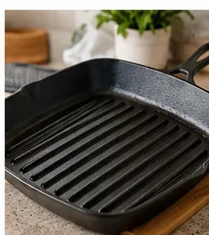 A clean black ridged grill pan resting on a kitchen counter with no visible food buildup.