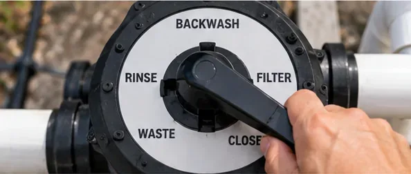 Prim-plan al unei valve multiport a unui filtru de nisip pentru piscină, care este mutată pentru etapa de clătire după spălarea în contracurent.