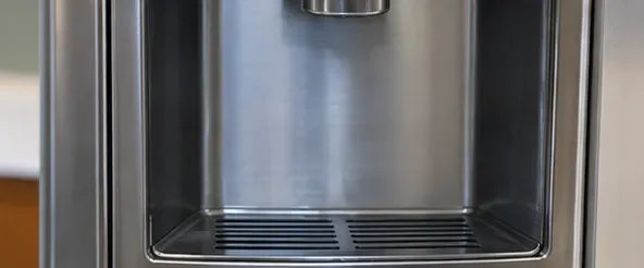 A clean, dry refrigerator dispenser recess with the drip area reassembled beneath the nozzle.