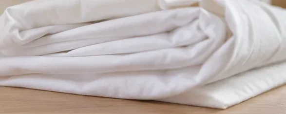 Clean white bed sheets folded loosely after successful stain removal