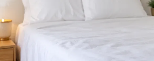 A neatly made bed with clean white sheets and pillows