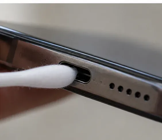 Close-up of a cotton swab being inserted into a USB-C charging port as an example of what not to do.