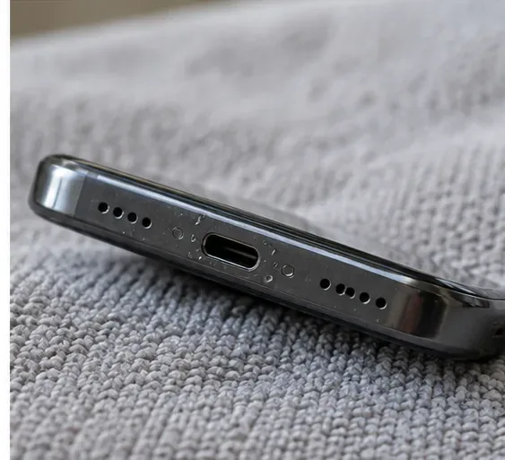 A smartphone resting on a dry microfiber cloth with its USB-C charging port angled downward.