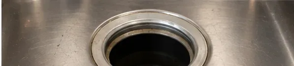 Clean stainless steel kitchen sink opening after the drain assembly has been removed