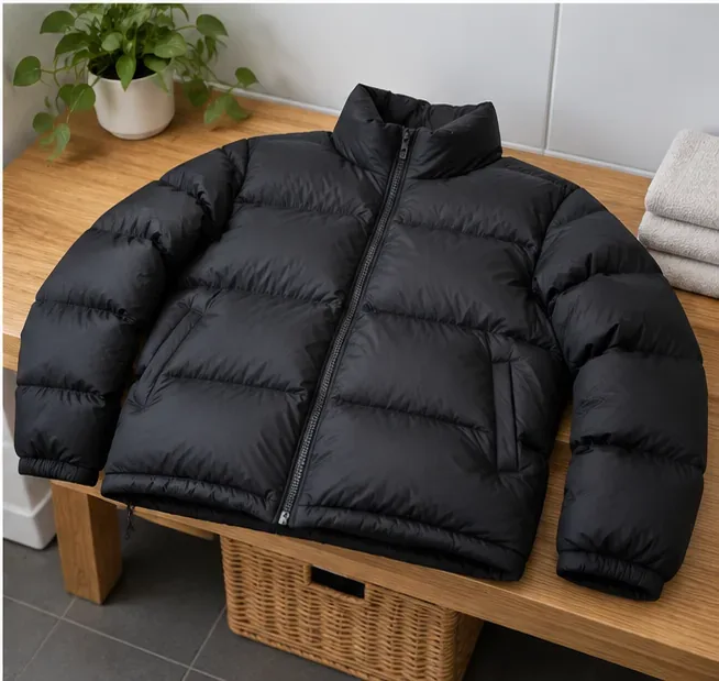A fully dry, evenly lofted black puffer lies flat on a wooden bench for a final check.