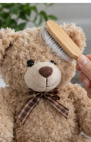 A hand gently brushing the dry fur on a clean teddy bear with a soft brush