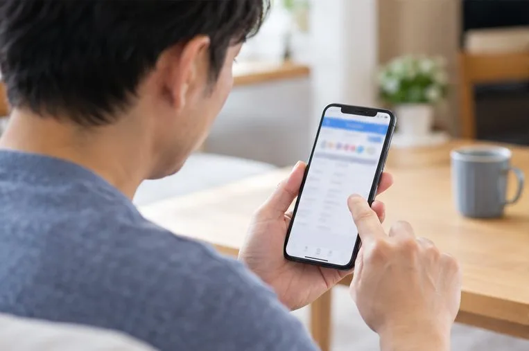 自宅でスマートフォンを使い宝くじの当せん結果ページを確認する人
