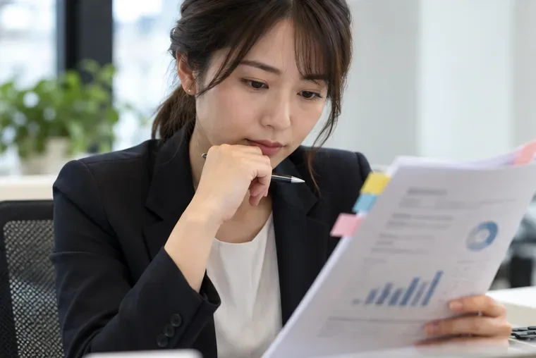 付箋の付いた決算説明資料を読み込む人